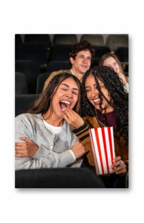 Friends laughing and sharing popcorn at the movie theater