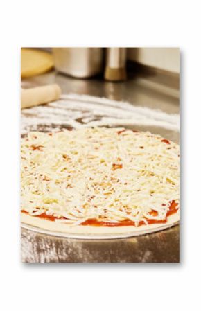 Dough is rolled out on a floured countertop while a plate with toppings sits nearby. The kitchen is warm and inviting, perfect for making a delicious meal