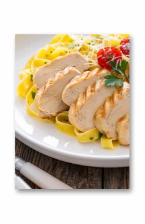 Grilled sliced chicken breast and pappardelle noodles on wooden background 