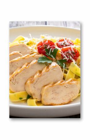 Grilled sliced chicken breast and pappardelle noodles on wooden background 