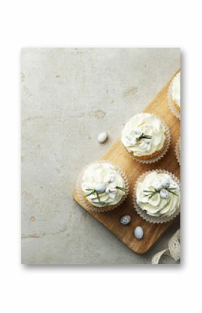Tasty Easter cupcakes with vanilla cream, candies and ribbon on gray table, flat lay. Space for text