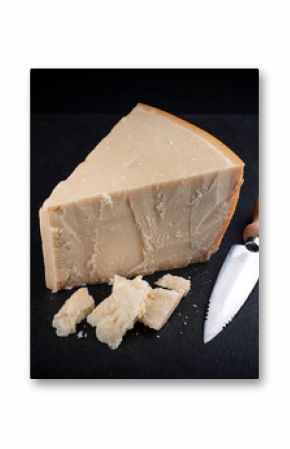 Traditional Parmesan cheese piece with cheese knife during food preparation as close-up on a black design board with text space