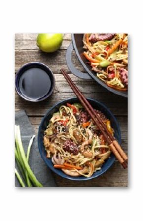 Stir-fry noodles with sea food and vegetables served on wooden table, flat lay