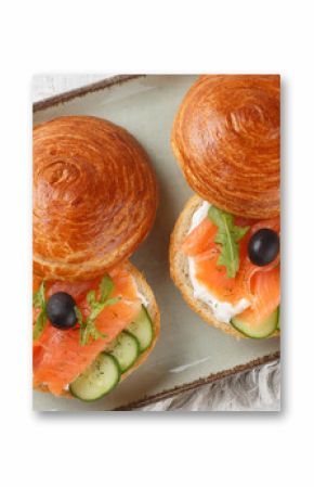 Sandwich with salted salmon, cream cheese, fresh cucumber and olives close-up on a plate on the table. Horizontal top view from above