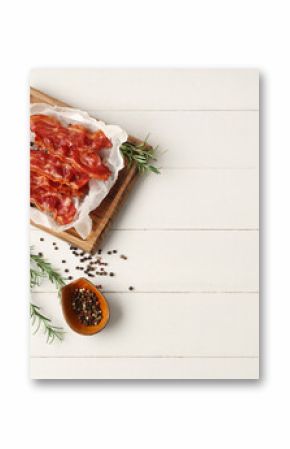 Cutting board with fried bacon rashers, rosemary and bowl of peppercorn on white wooden background