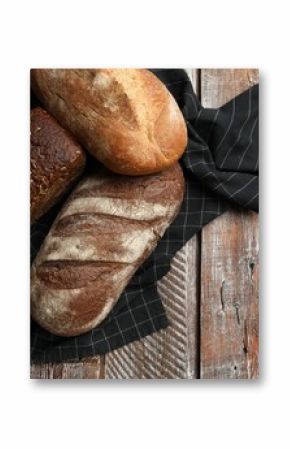 Different types of fresh bread on wooden table, flat lay. Space for text
