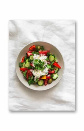 Fresh vegetable salad with stracciatella cheese and fresh cilantro on a light background, top view