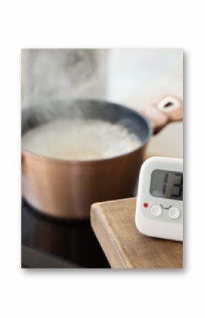 Modern kitchen timer on table against cooking pot in room, closeup