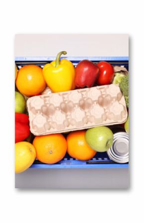 Plastic shopping basket full of products on light background, top view