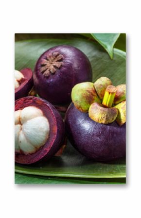 Mangosteen fruits on green leaves close up.