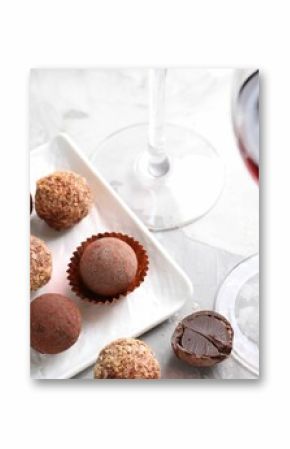 Red wine in glass and truffle bonbons on light table, closeup