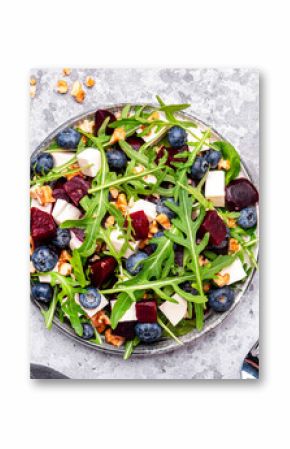 Gourmet salad with beet, blueberries, cheese, arugula and walnuts, gray table background, top view