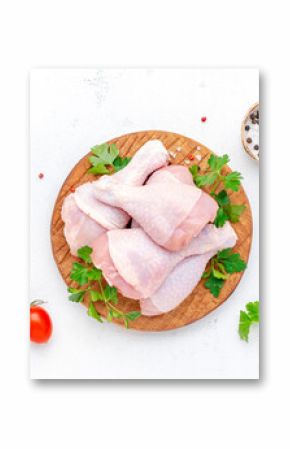Raw chicken legs or drumsticks on wooden board with pepper, salt and parsley, top view