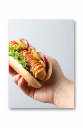 Woman with tasty hot dog on light grey background, closeup