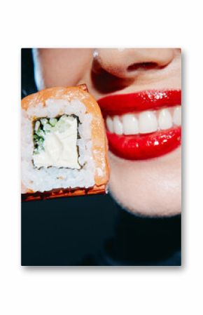 Young woman with red lips smiling while holding sushi with chopsticks, showcasing vibrant colors and a modern dining concept.