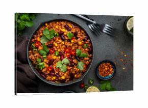 Tex-mex meet chili con carne with beef, red beans,, sweet corn, cilantro in frying pan, rusty green background top view