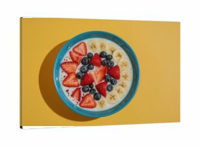 Fresh berry and fruit smoothie bowl served on a vibrant blue dish with contrasting yellow shadow