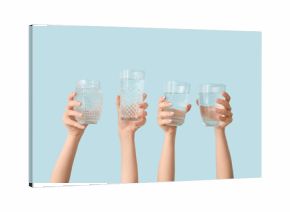 Female hands with glasses of cold water on blue background