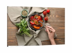 Female hand with fork and bowl of fresh tomato salad on wooden background