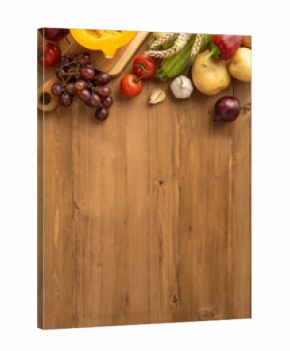 Vertical view of a Thanksgiving harvest featuring fresh fruits, vegetables, and wheat on a wooden surface
