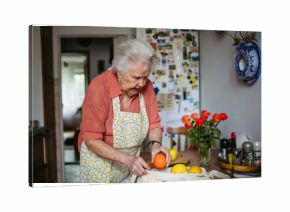 Senior lady in apron preparing fresh fruit at home.