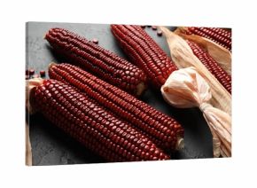 Ripe red corn cobs and kernels on dark textured table, closeup