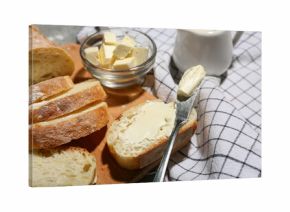 Wooden board with sliced bread, butter and jug of cream on grey grunge background