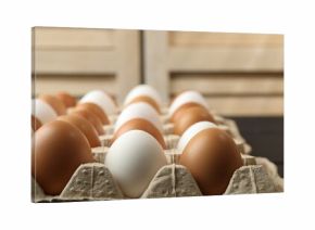 Many raw chicken eggs in carton on table indoors, closeup
