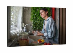 Woman washing dishes at kitchen sink, doing housework