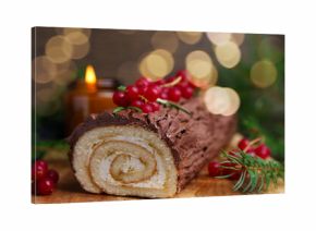 Delicious Yule log (traditional Christmas cake) with redcurrant and fir tree branches on table, closeup