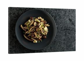 Fried shimeji mushrooms with thyme and garlic on a black plate.