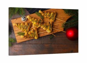 Christmas trees made with puff pastry, pesto sauce, cheese and festive decor on wooden table, flat lay. Space for text