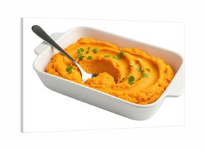 Creamy orange vegetable puree, possibly from carrots or sweet potatoes, served in a white ceramic baking dish with a spoon and garnished with fresh microgreens, isolated on black