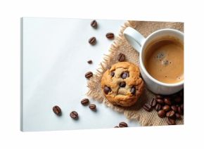 White cup of hot espresso coffee stands beside yummy chocolate chip cookie. Fresh roasted coffee beans, rustic burlap fabric create warm, inviting morning scene. Isolated top view presents perfect