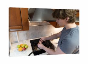Cracking egg into hot pan caucasian young man cooking homemade breakfast in small kitchen doing simple morning routine preparing food. Healthy Breakfast. Home Kitchen Lifestyle