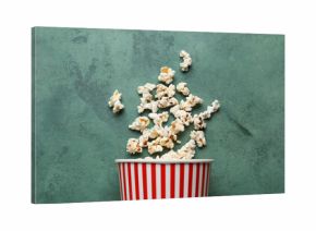 Bucket with tasty popcorn on green background