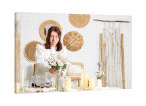 Pretty young woman serving table with beautiful flowers in dining room
