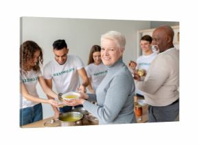 A happy elderly woman smiles as she receives soup from a volunteer group dedicated to helping seniors with free meals and donation boxes. This community effort fosters companionship and care.