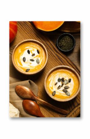 Delicious pumpkin soup served on wooden table, top view