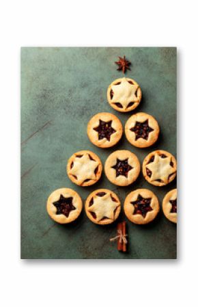 Christmas and New Year food Background with fir tree made from traditional christmas Mince pies, anise stars and cinnamon stickes on a green table surface.