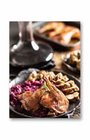 Portion of roast duck leg red cabbage homemade dumplings on plate and red wine on the background