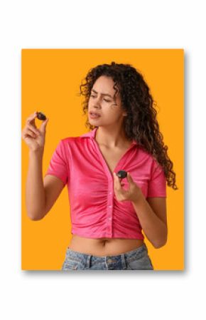 Beautiful young African-American woman with sweet chocolate candies on yellow background