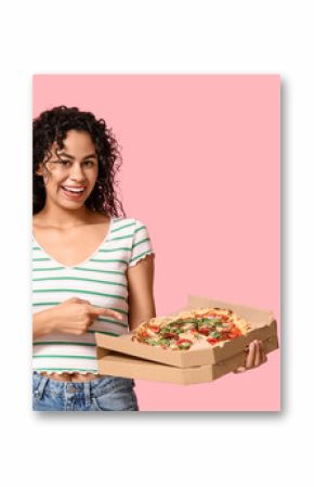 Beautiful young happy African-American woman pointing at delicious pizza on pink background