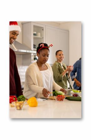 Wearing christmas hats, multiracial friends preparing festive meal in kitchen, spirit, at home