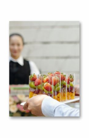 Close-up of person serving fruits in glass during catering service