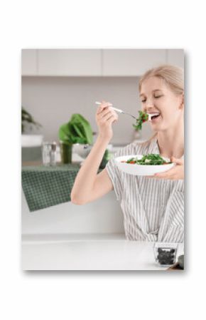 Young woman eating salad with feta cheese in kitchen