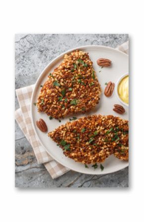 Crispy chicken in pecan crust with spicy sauce close-up in a plate on the table. horizontal top view from above