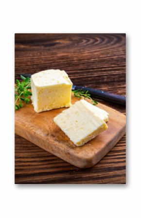 Fresh French sea salt butter garnished with thyme offered as close-up on a rustic wooden chopping board