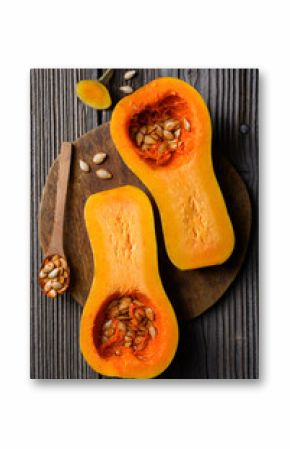 Top view of raw butternut squash with wooden spoon and seeds on wooden cutting board. Halfs of pumpkin close up. Food photography