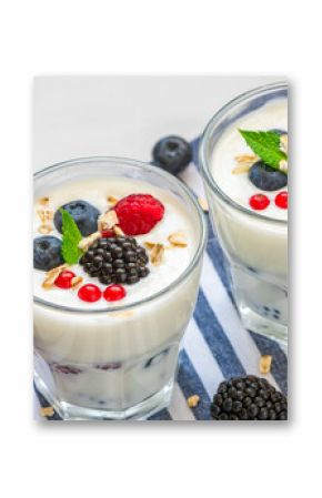 Greek yogurt with fresh berries, oats and mint in glasses on white background. Yoghurt with blueberry, raspberry, blackberry and granola. Healthy breakfast. Diet food